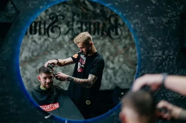 Barber strihá zákazníka, pohľad do okrúhleho zrkadla